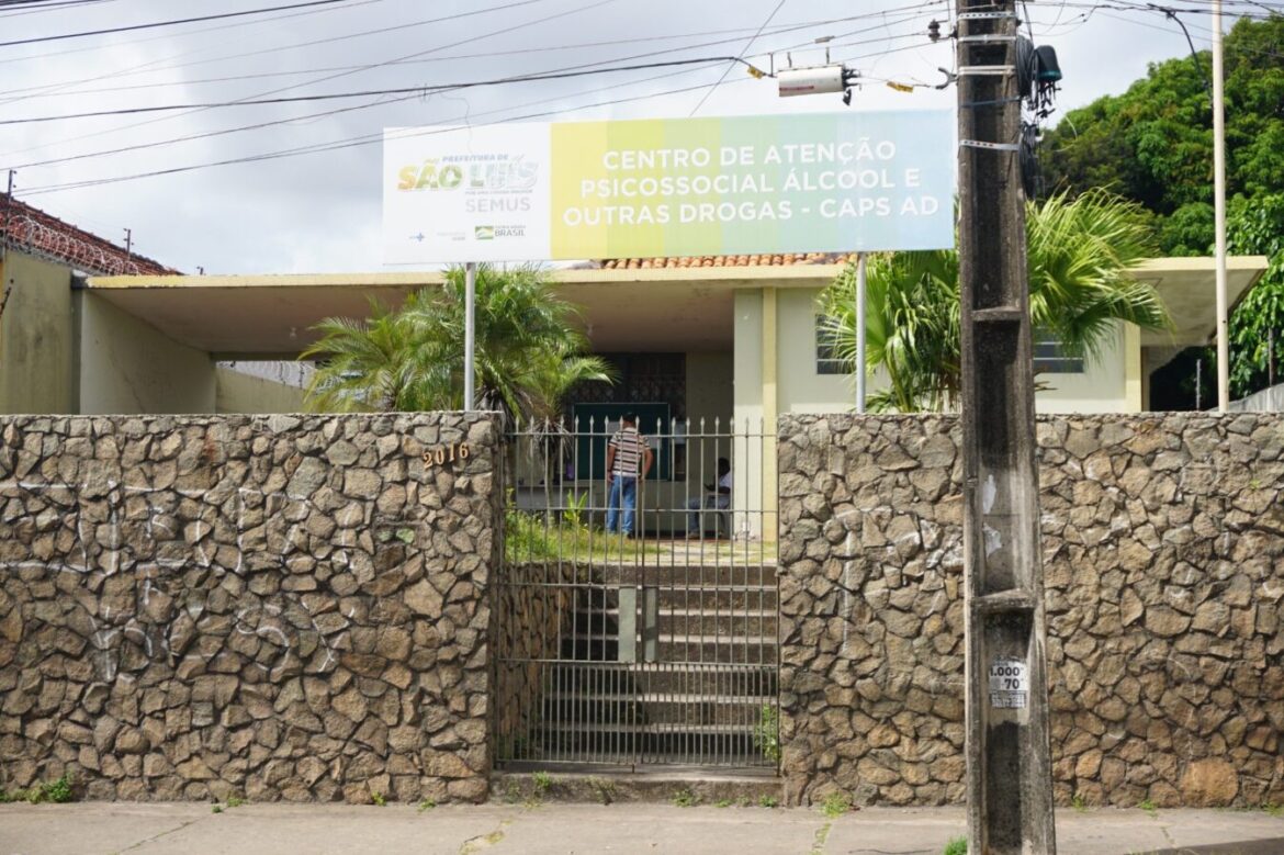 Fachada do Caps ad (Centro de Atenção Psicossocial Álcool e outras Drogas) em São Luís, com placa institucional verde e branca identificando a unidade, muro de pedras e portão de entrada.